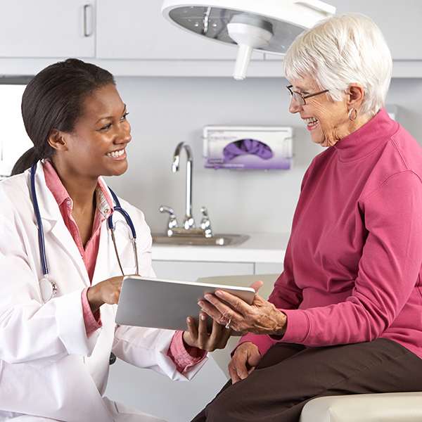 A doctor confronts a smiling senior with good news Doctor Discussing Records With Senior Female Patient Smiling